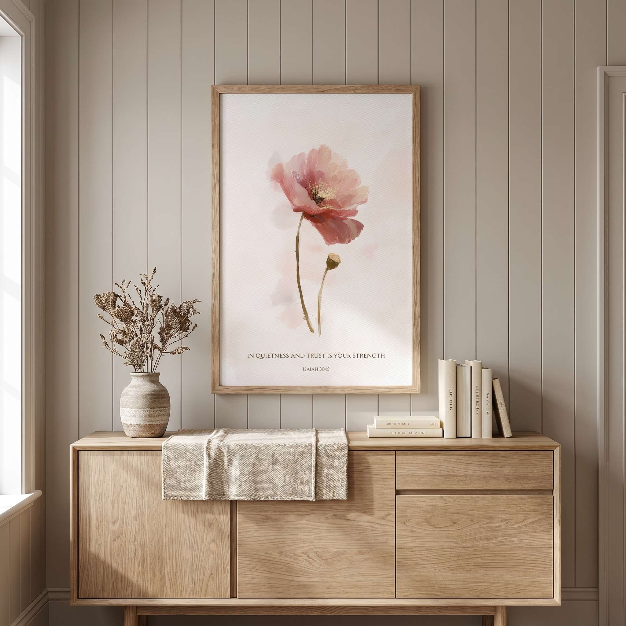 Framed Christian floral wall art titled Isaiah 30:15 featuring a watercolor poppy flower with "In quietness and trust is your strength", displayed on a beige paneled wall above a light wooden sideboard in a soft organic modern dining room.