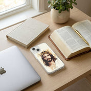Phone case with a portrait of a bearded figure on a desk with books and a laptop.