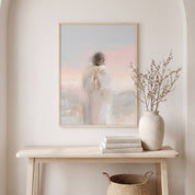 Watercolor Christian wall art of Jesus holding the lost sheep, displayed in a bright entryway above a console table with a vase and books.