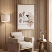Minimalist line art print of Jesus washing feet in a light wood frame hanging on a slatted wood wall above a cozy beige armchair.