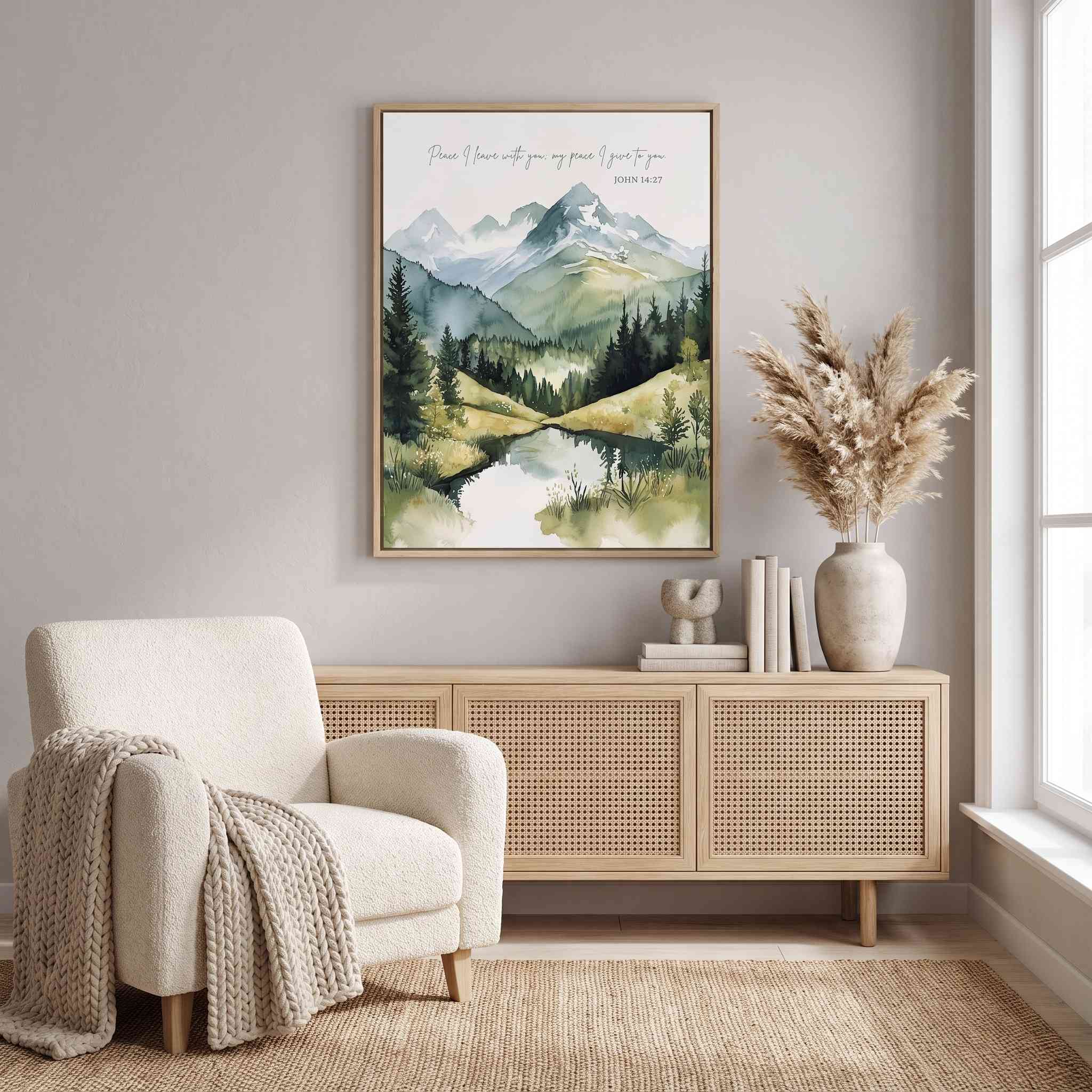 Framed John 14:27 Christian landscape wall art with watercolor mountains, pine trees, and a lake above a wood sideboard in a bright living room.
