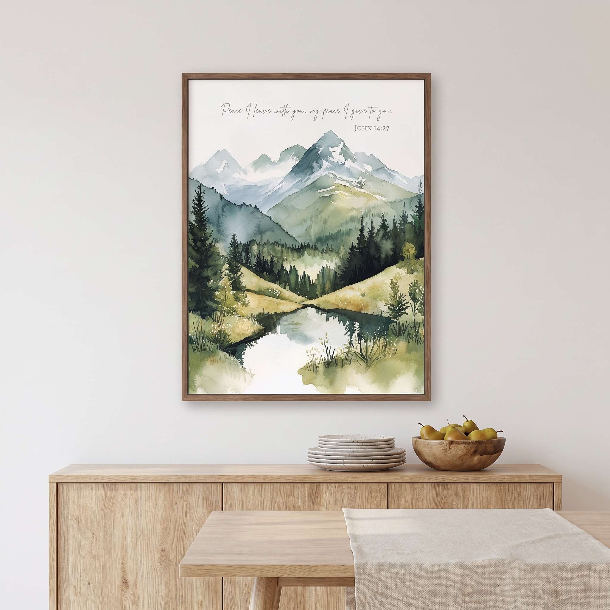 Framed John 14:27 Christian wall art showing a watercolor mountain landscape, pine forest, and reflective lake above a dining room sideboard.