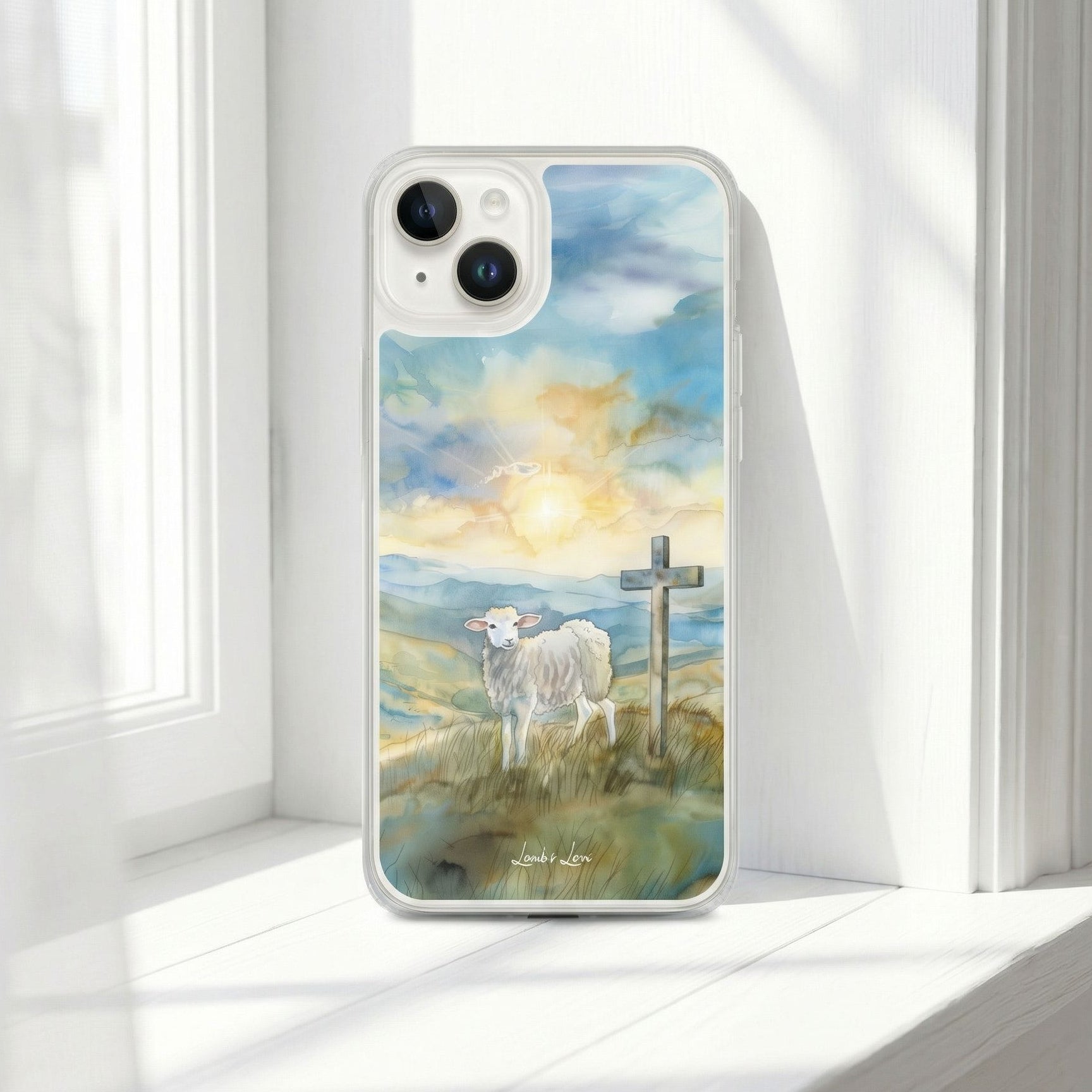 Phone case with a painting of a sheep and cross on a hillside, placed on a white surface.