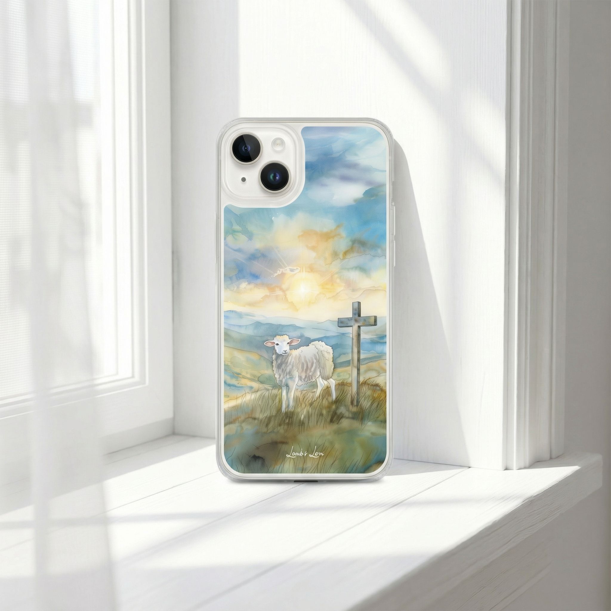 Phone case with a painting of a sheep and cross on a hillside, placed on a white surface.