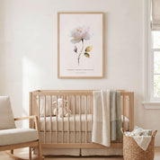 Framed Christian floral wall art titled Lamentations 3:22–23 featuring a watercolor rose with "His mercies are new every morning", displayed on a warm beige wall above a wooden crib in a bright neutral nursery.