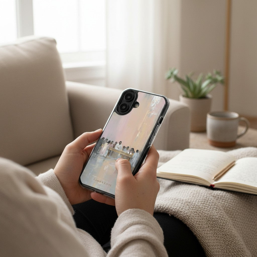 Last Supper MagSafe® clear iPhone case featuring Jesus and the disciples, held in a cozy living room setting beside a devotional journal and coffee mug