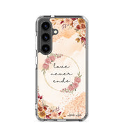 Love Never Ends Christian Samsung Galaxy S24 phone case with soft floral wreath design featuring 1 Corinthians 13:8 Bible verse on clear protective case