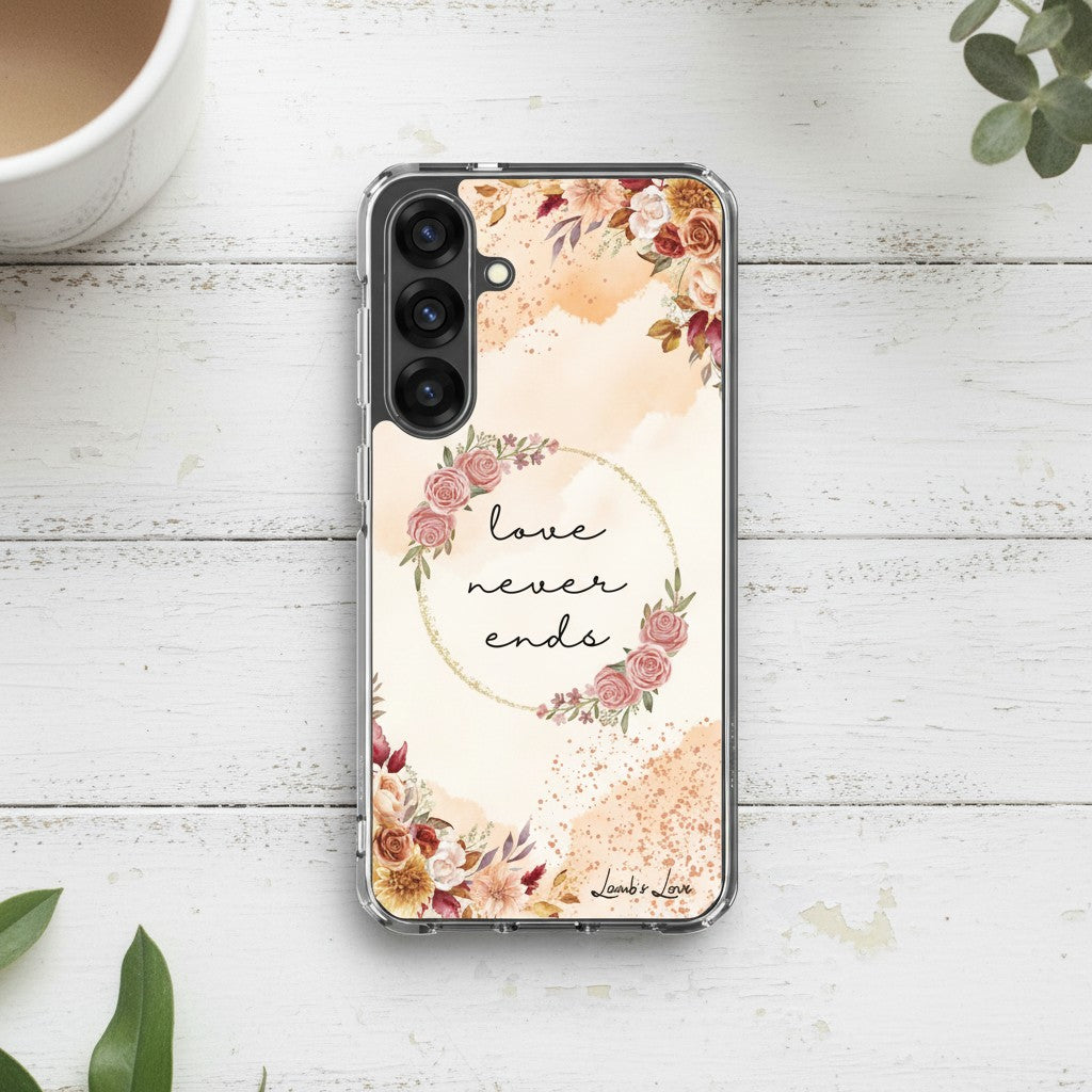 Love Never Ends Christian Samsung Galaxy phone case with a delicate pink floral wreath design and 1 Corinthians 13:8 Bible verse on a white wood background.