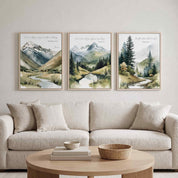 Three framed vintage Christian mountain landscape wall art prints featuring Matthew 28:20, John 14:27, and Psalm 46:10 Scripture verses, displayed as a 3-piece triptych above a cream sofa in an organic modern living room.