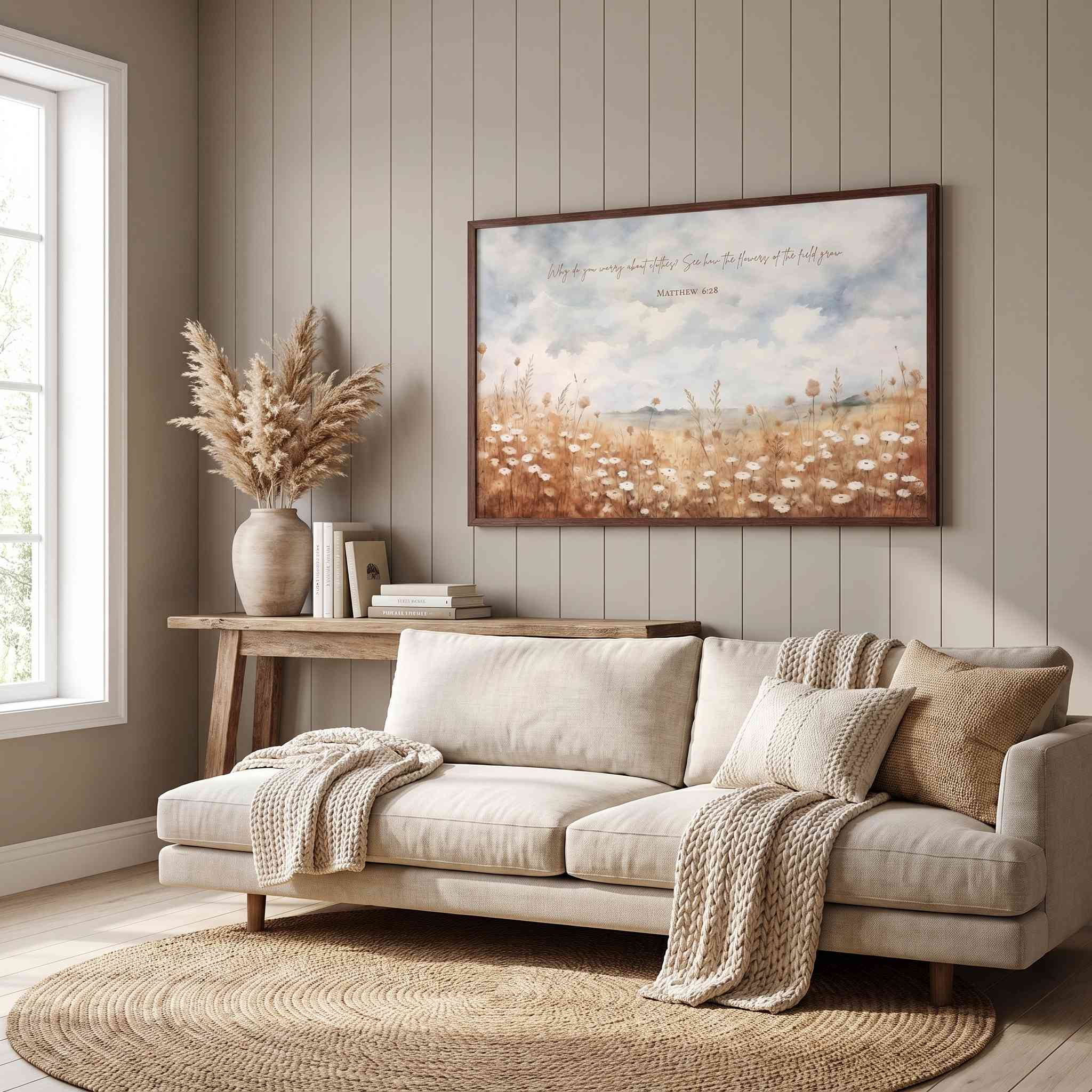Matthew 6:28 Scripture wall art featuring a peaceful wildflower meadow, styled above a cream sofa in a cozy neutral living room.