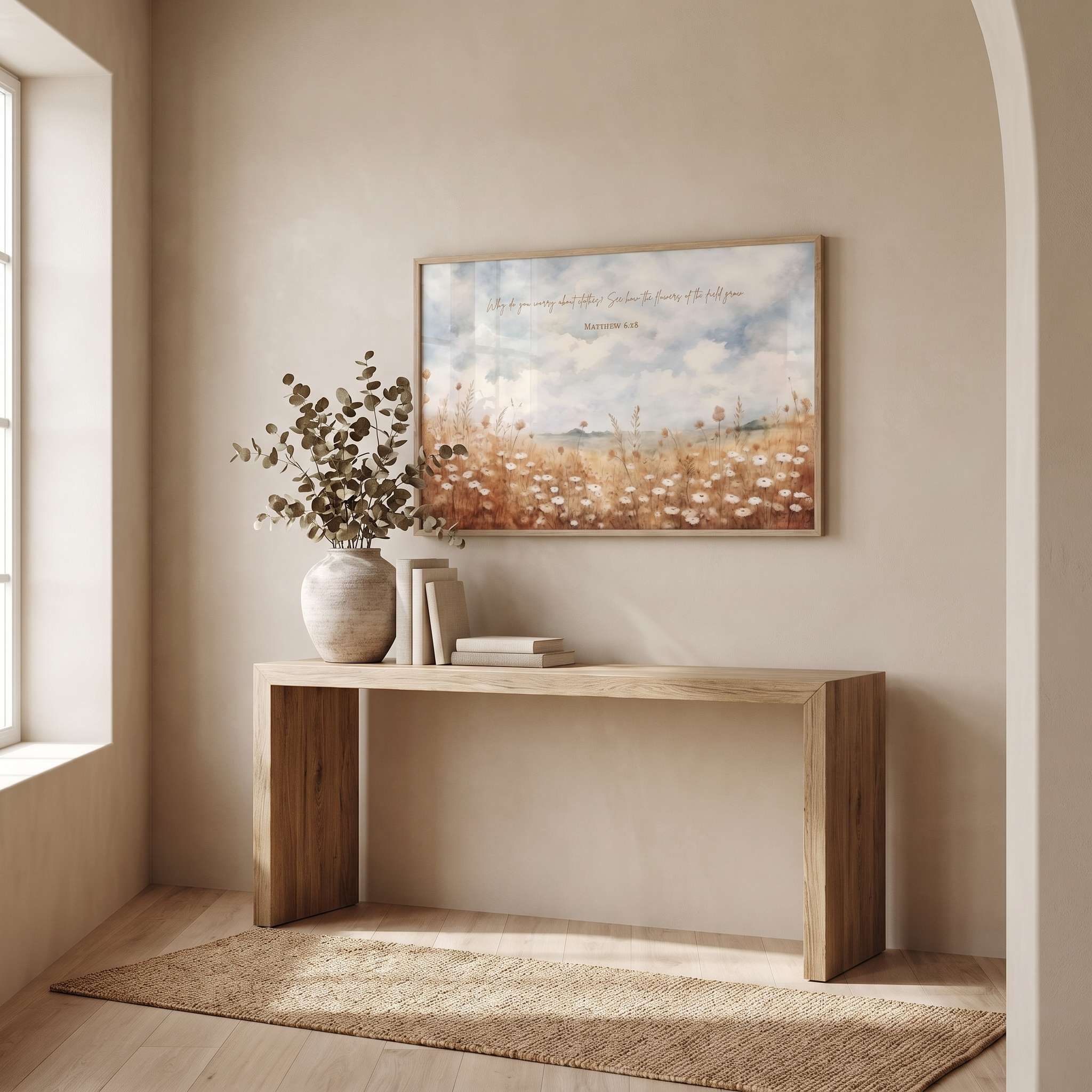 Matthew 6:28 wildflower wall art showing a peaceful field of white blossoms, displayed above a light wood console table in a bright entryway.