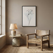 Minimalist Lily Line Art in a sleek black frame, hanging above a rustic wooden armchair and a stone-style side table with a ceramic lamp in a warm beige room.