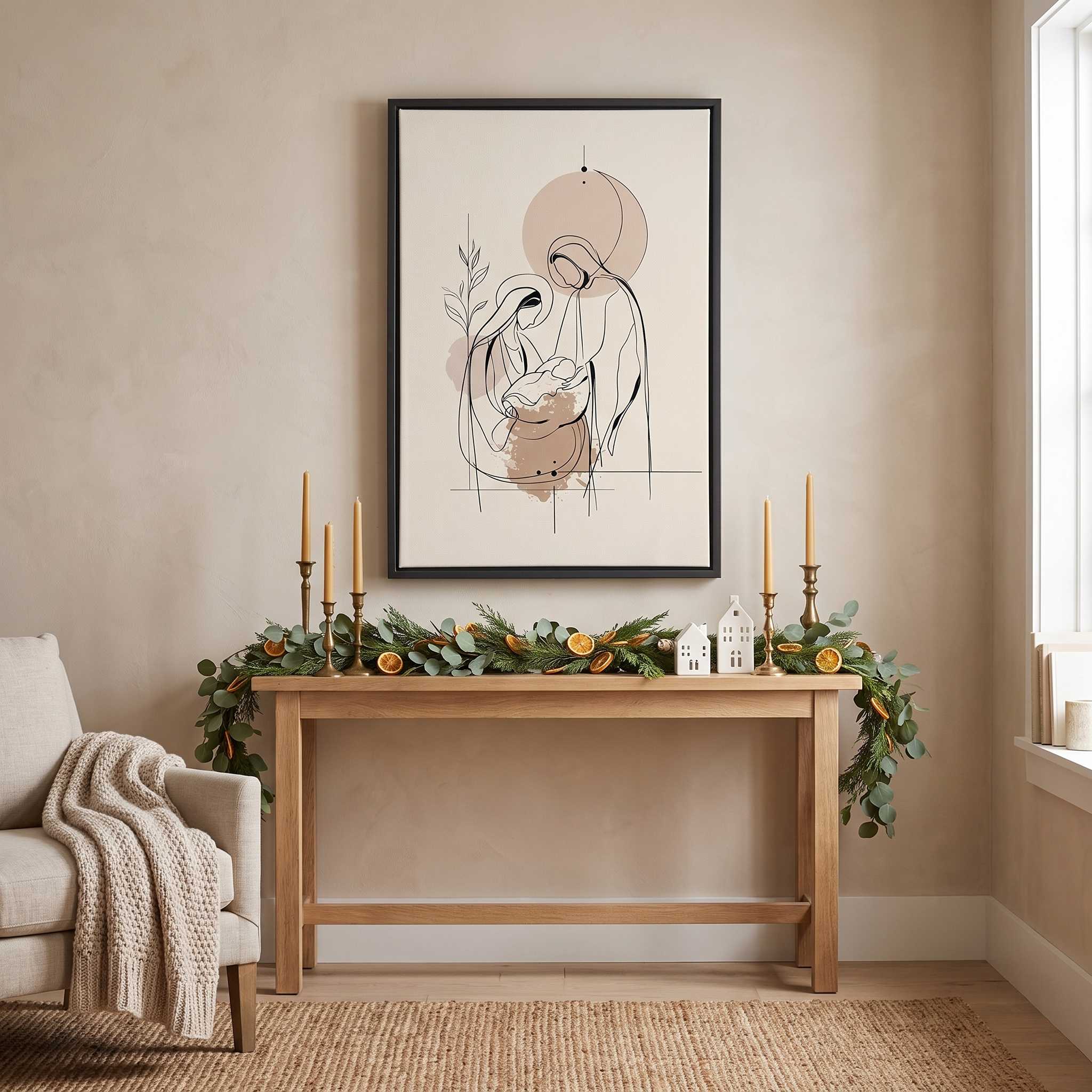 Minimalist line art print of the Holy Family in a black frame hanging on a beige wall above a wooden console table with Christmas garland and candles.