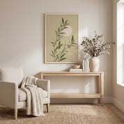 Minimalist olive branch vertical framed canvas Christian wall art in soft sage green with rising sun displayed on a beige wall above a light wood console table in an organic modern living room.