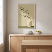 Minimalist olive branch in a white ceramic vase vertical framed canvas Christian wall art in soft sage green displayed on a light gray wall above a wooden sideboard in an organic modern dining room.