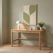 Minimalist olive leaf vertical framed canvas wall art in soft sage green displayed above a light wood desk in an organic modern workspace with a mushroom lamp and small plant.