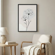 Minimalist Rose Line Art in a black frame hanging above a neutral armchair and wooden side table in a bright, modern living room.