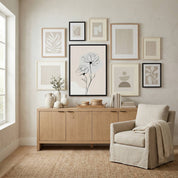 Minimalist Rose Line Art featured as the center of a neutral gallery wall set above a wooden sideboard and beige armchair.
