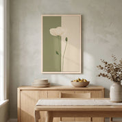 Minimalist white poppy vertical framed canvas wall art displayed on a textured wall above a light wood sideboard in an organic modern dining room.