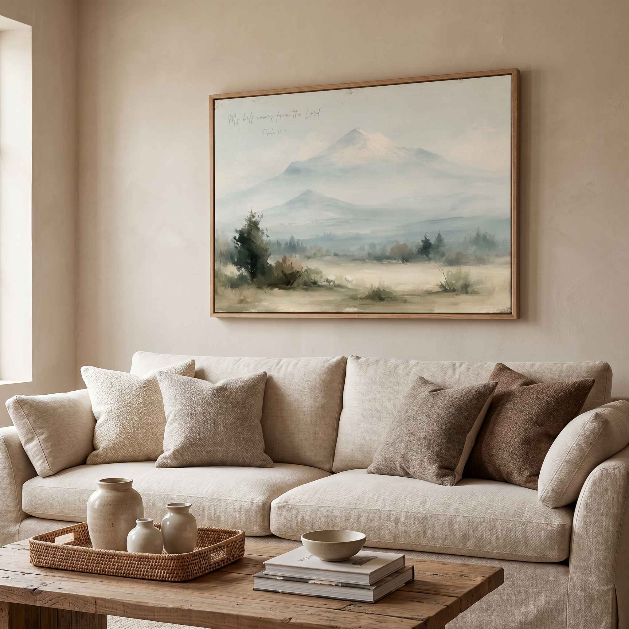 Framed vintage Psalm 121:2 Christian landscape canvas wall art featuring snow-capped mountains hanging on a beige wall above a cream sofa in a styled living room.