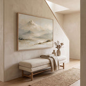 Framed vintage Psalm 121:2 Christian landscape canvas wall art featuring snow-capped mountains hanging on a textured beige wall in a staircase hallway above an upholstered bench with a throw blanket, ceramic vases, and a jute runner.