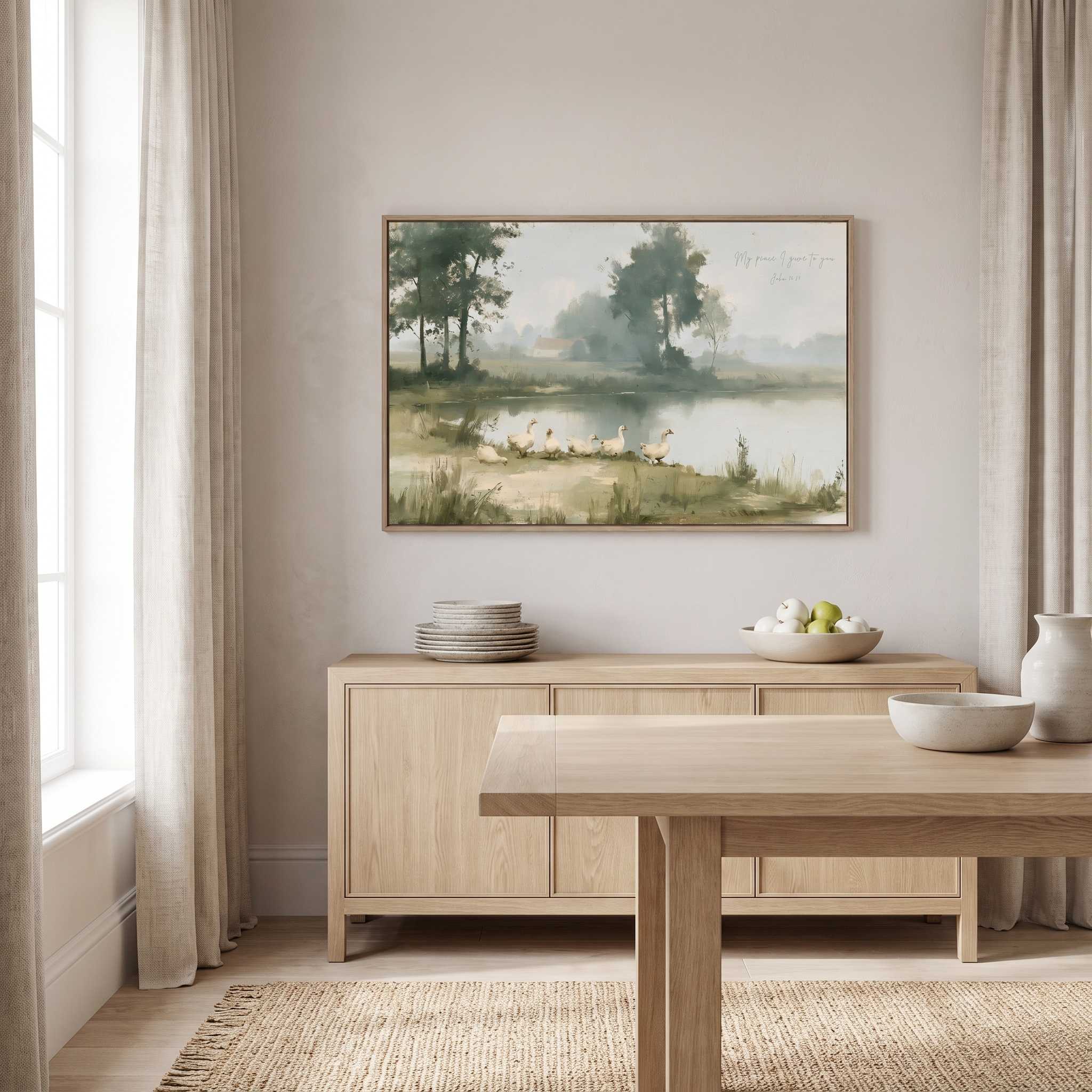 Framed vintage John 14:27 landscape canvas wall art hanging above a light wood sideboard in a bright Scandinavian dining room.