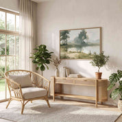 Framed vintage John 14:27 landscape canvas wall art hanging above a rattan console table and armchair in a sunlit organic modern room.