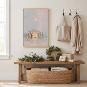 Framed Nativity wall art above an entryway bench with a Christmas wreath, greenery and wrapped gifts, for a welcoming Christian holiday home.