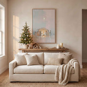 Framed Nativity Christmas wall art above a beige sofa beside a decorated Christmas tree, creating a peaceful Christian holiday living room.