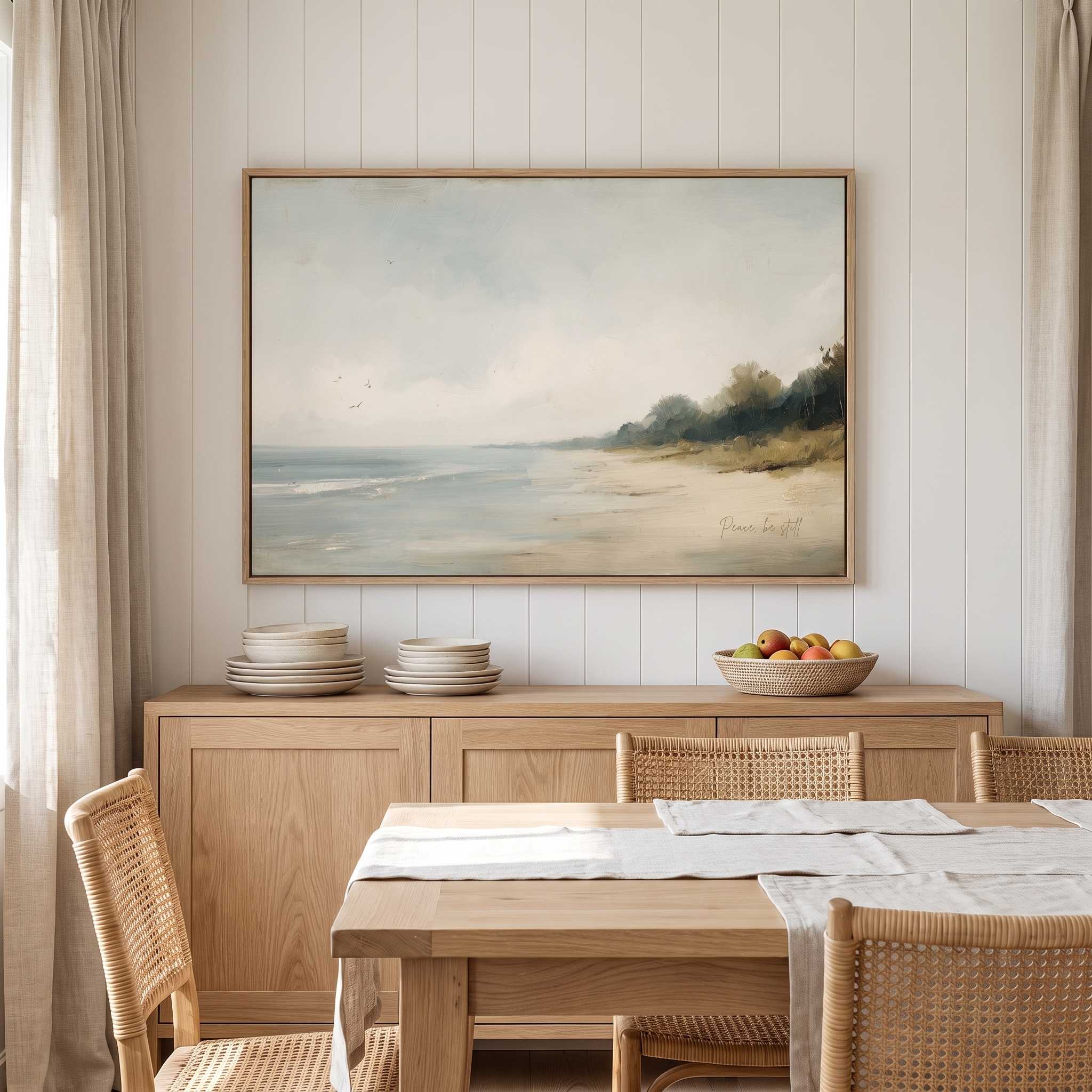 Framed vintage Mark 4:39 Christian landscape canvas wall art featuring a coastal beach scene hanging above a wooden sideboard with stacked plates and a fruit bowl in a warm dining room.