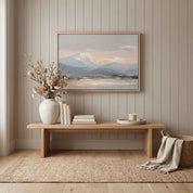 Framed Peace in the Mountains Christian landscape wall art featuring snowy peaks and a reflective lake, styled above an entryway bench with a vase and candle.