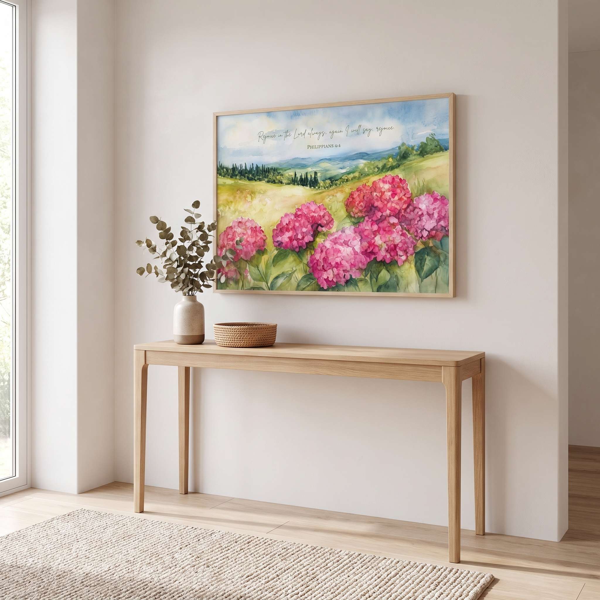 Framed Philippians 4:4 hydrangea wall art displayed above a console table in a bright neutral living room.