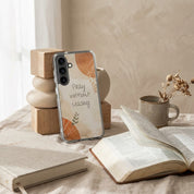 Christian Samsung Phone case with 'Pray without ceasing' text on a table with books and a mug.