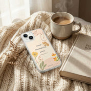 Phone case with floral design and text on a textured surface with a cup of coffee and book.