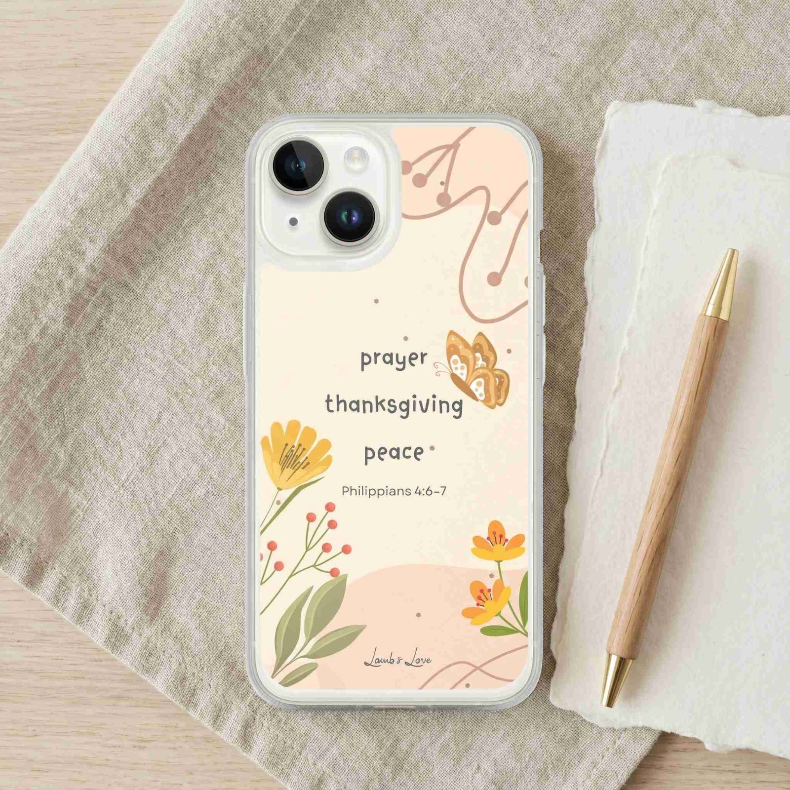 Phone case with floral design and text on a fabric surface with a pen