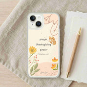 Phone case with floral design and text on a fabric surface with a pen