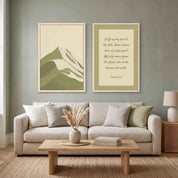 Two-piece framed canvas gallery wall set featuring Psalm 121:1–2 Scripture art and a minimalist sage green mountain landscape print, displayed in light wood frames on a sage green wall above a light beige sofa and oak coffee table in a modern organic living room.