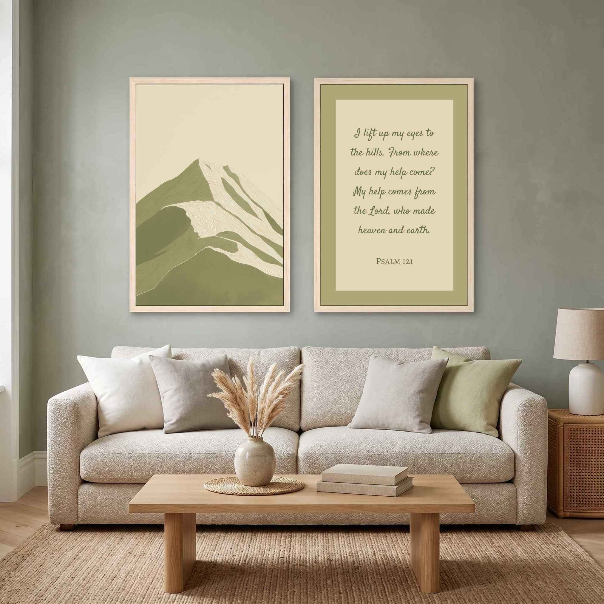 Two-piece framed canvas gallery wall set featuring Psalm 121:1–2 Scripture art and a minimalist sage green mountain landscape print, displayed in light wood frames on a sage green wall above a light beige sofa and oak coffee table in a modern organic living room.