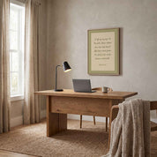 Framed minimalist Scripture wall art titled Psalm 121:1–2 featuring "My help comes from the Lord" in elegant script, displayed in a light wood frame on a beige wall above a wooden desk with a black lamp, laptop, mug, and chair with a knitted throw in a softly lit home office.