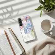 Fearfully and Wonderfully Made Christian Samsung Galaxy phone case with watercolor floral design, placed on a sun-drenched white surface with soft shadows, an open Bible, and a white coffee mug.