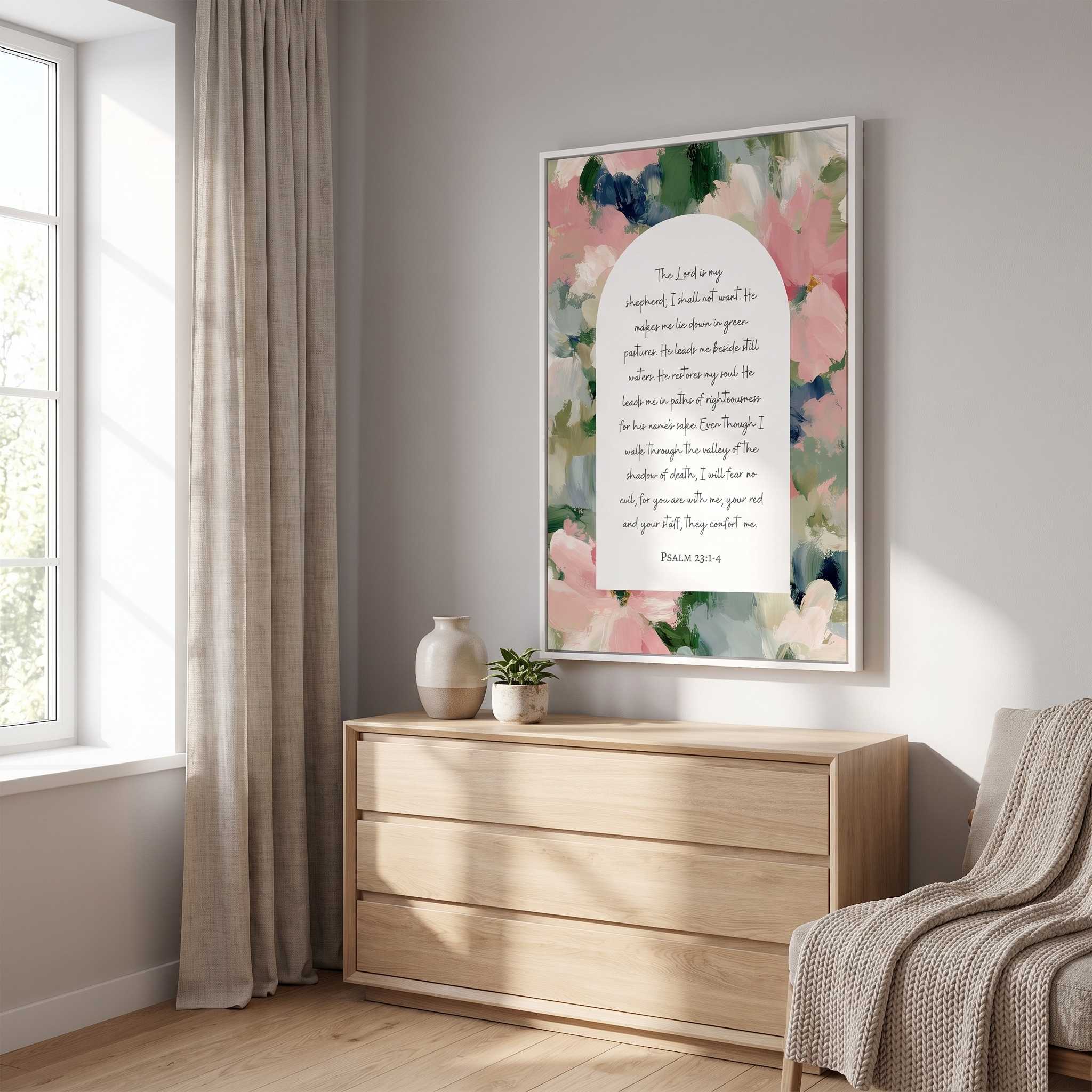 Framed vintage Christian floral wall art titled Psalm 23:1–4 featuring "The Lord is my shepherd" with watercolor botanical artwork, displayed in a white frame on a light wall above a wooden dresser in a bright Scandinavian bedroom.