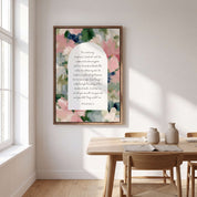 Framed vintage Christian floral wall art titled Psalm 23:1–4 featuring "The Lord is my shepherd" with watercolor botanical artwork, displayed on a beige wall above a wooden dining table in a sunlit Scandinavian dining room.