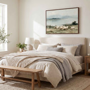 Framed Psalm 23 vintage landscape canvas art above a bedroom bed, depicting sheep grazing beside calm waters in a serene rustic bedroom.