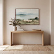 Framed Psalm 23 vintage landscape canvas art above a wooden entryway console table, depicting sheep grazing beside calm waters in a bright rustic entryway.