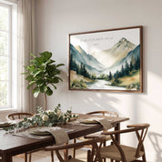Framed vintage Christian mountain landscape wall art titled Psalm 33:5 featuring mountains, pine trees, and a river, displayed on a light wall above a wooden dining table in a bright modern dining room.