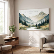 Framed vintage Christian mountain landscape wall art titled Psalm 33:5 featuring mountains, pine trees, and a river, displayed on a light beige wall above a armchair and sofa in an organic modern living room.