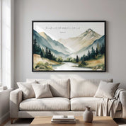 Framed vintage Christian mountain landscape wall art titled Psalm 33:5 featuring mountains, pine trees, and a river, displayed above a beige sofa in a modern minimalist living room.