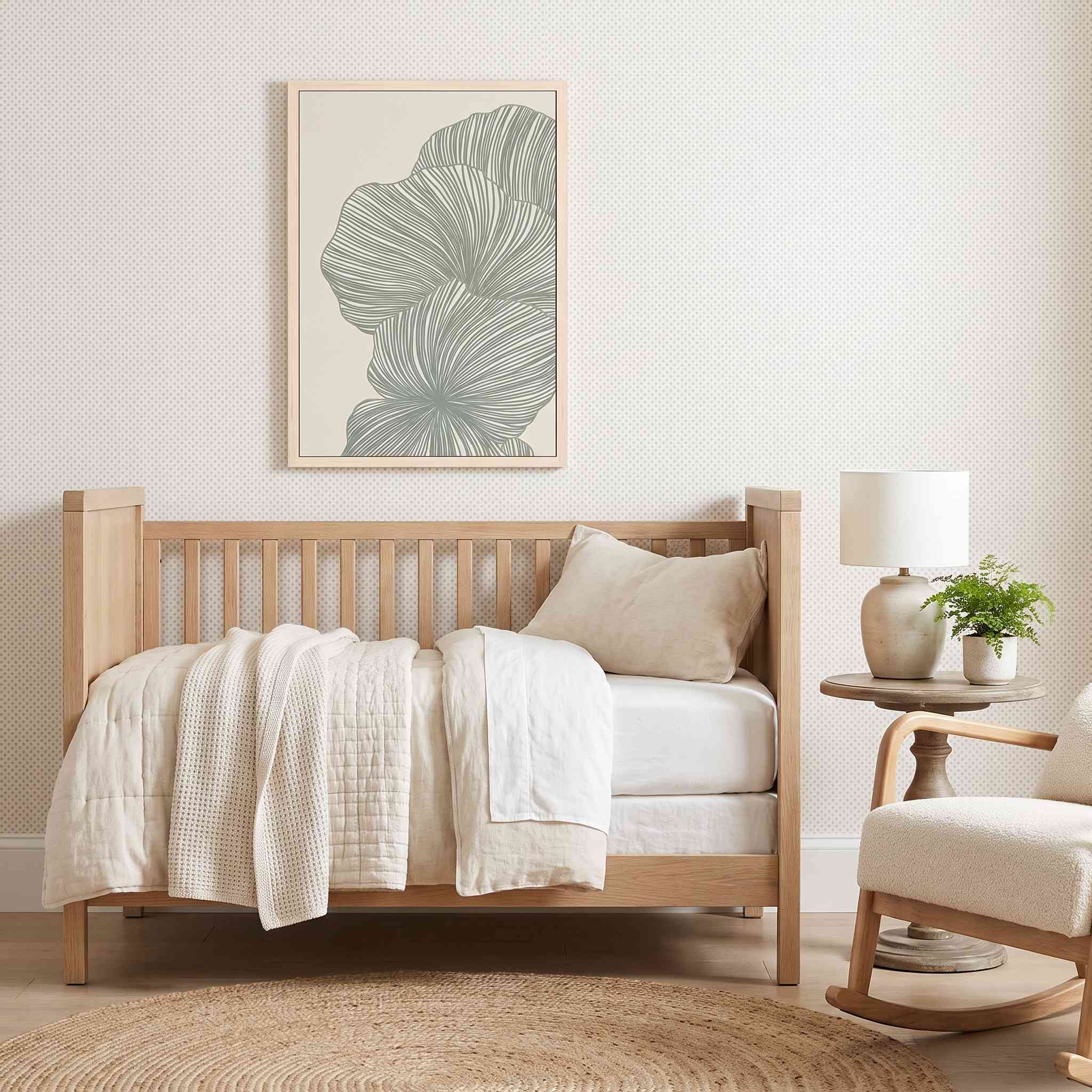 Framed minimalist palm leaf Scripture wall art titled Psalm 92:12–15 featuring "Flourish in Faith" with green line art artwork, displayed in a light wood frame on a subtle patterned wall above a light natural wood daybed and side table in a bright organic modern nursery.