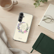Rejoice in Hope Christian Samsung phone case with lavender floral wreath and Romans 12:12 Bible verse, shown on a wooden desk next to a notebook, reading glasses, a cup of coffee, and greenery.