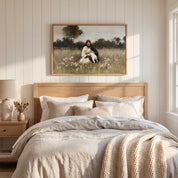Framed vintage Christian wall art titled Rest in the Shepherd, depicting Jesus holding a lamb in a wildflower meadow, displayed above a bed in a soft organic modern bedroom.